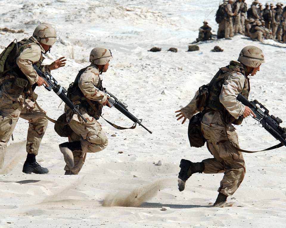 US marines run through the desert with guns